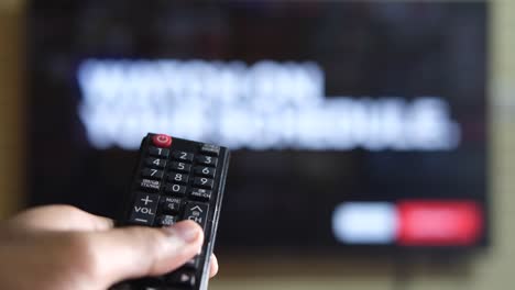 person holding a tv remote in front of a tv screen