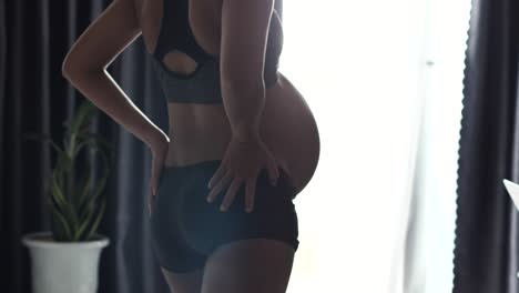 close up on a pregnant woman doing stretching, yoga pose exercise at home.