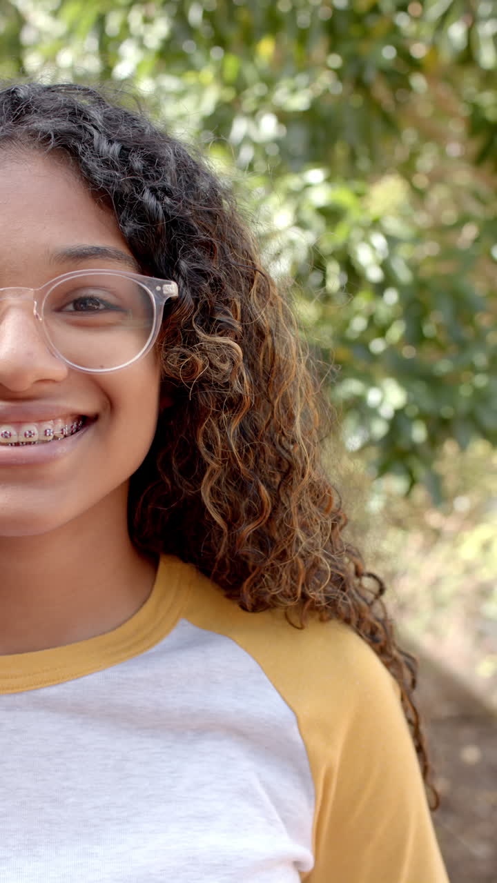 Vertical video: Smiling teenager with braces and glasses, enjoying outdoor school break