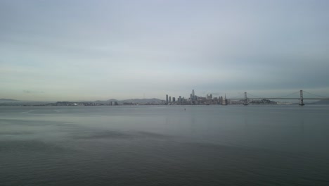 a rotating drone shot displays the bay bridge in the distance of the san francisco bay.