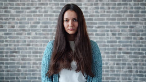 woman with long hair in front of brick wall