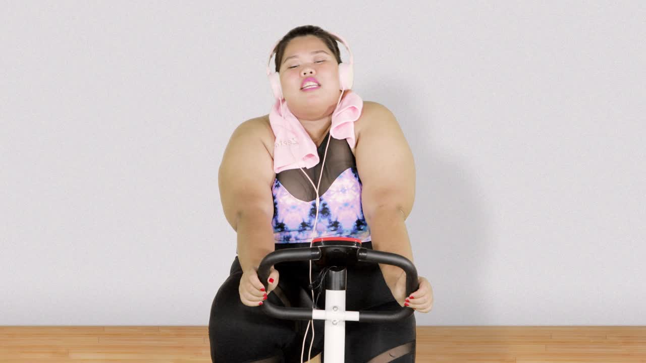 비만 한 여자 가 운동 자전거 를 타고 운동 하고 있다