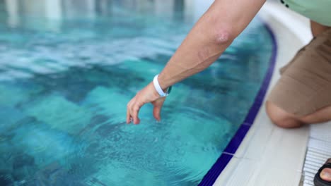 person touching water in a swimming pool