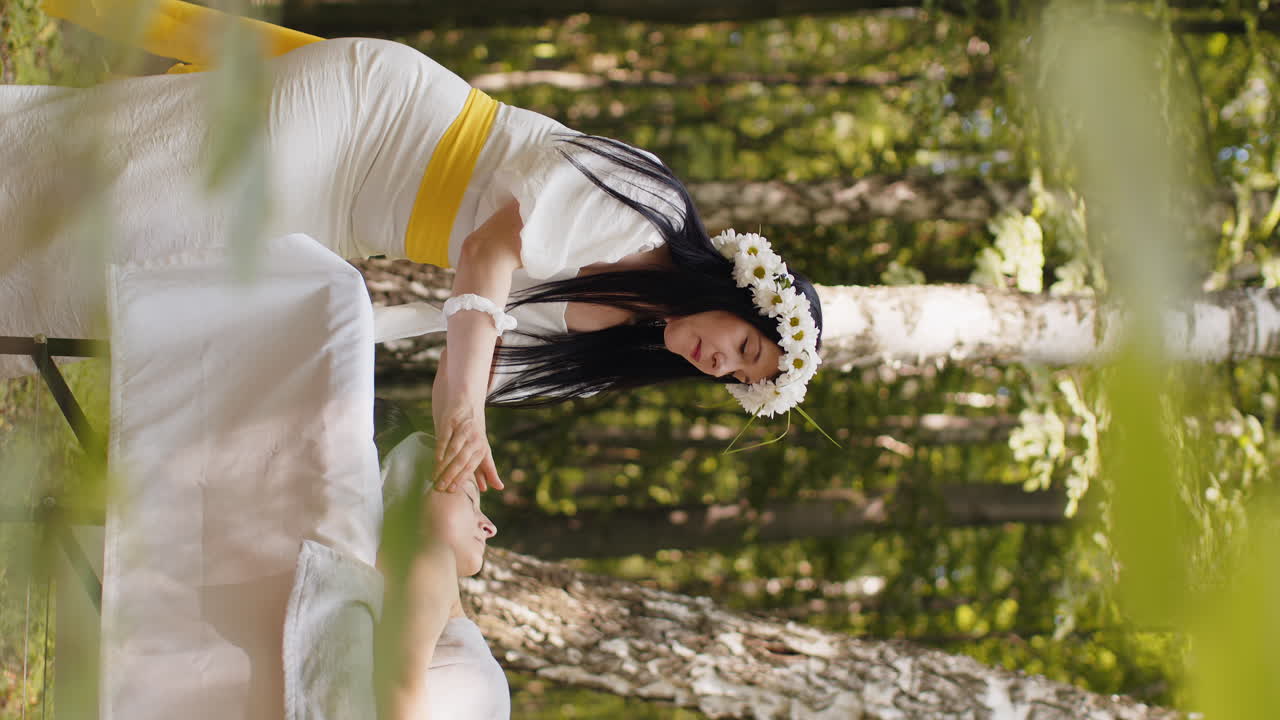 치료사 여성 의사는 숲에서 야외에서 손으로 스파 얼굴 마사지를하는 여성을 편안하게 만니다.