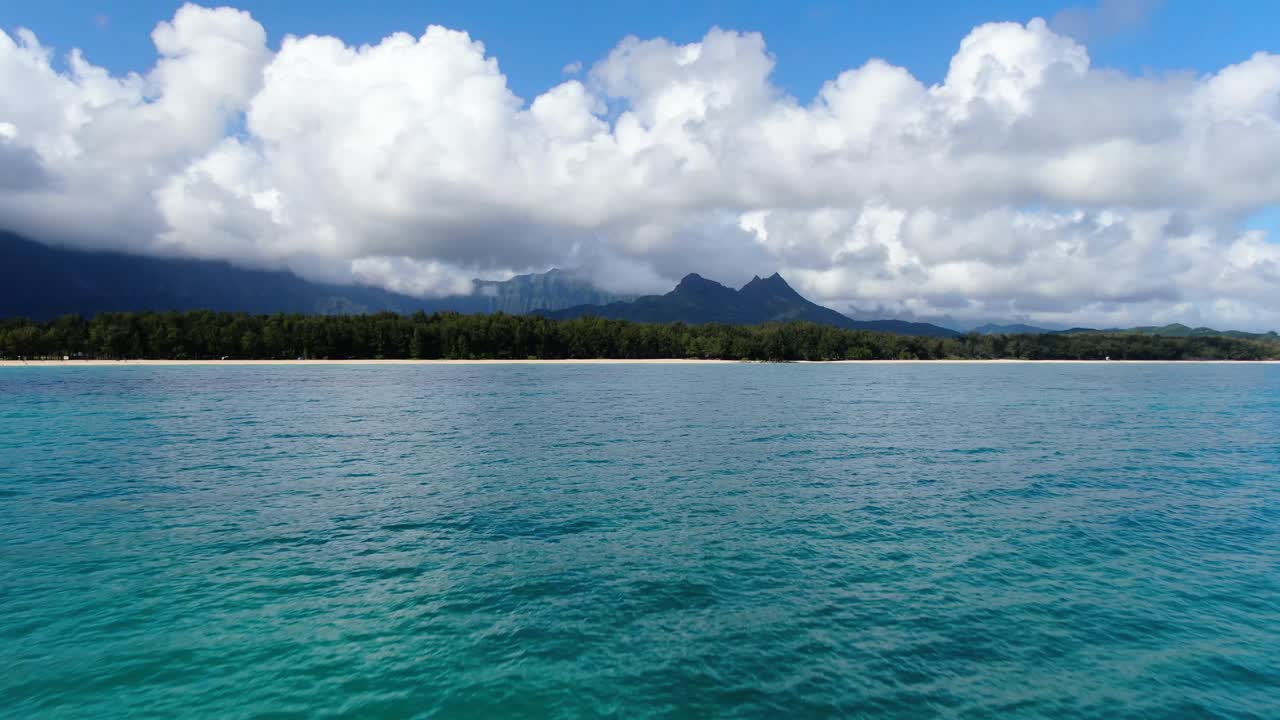 flying fast toward empty tropical hawaiian beach hidden by the jungle forest and mountain range