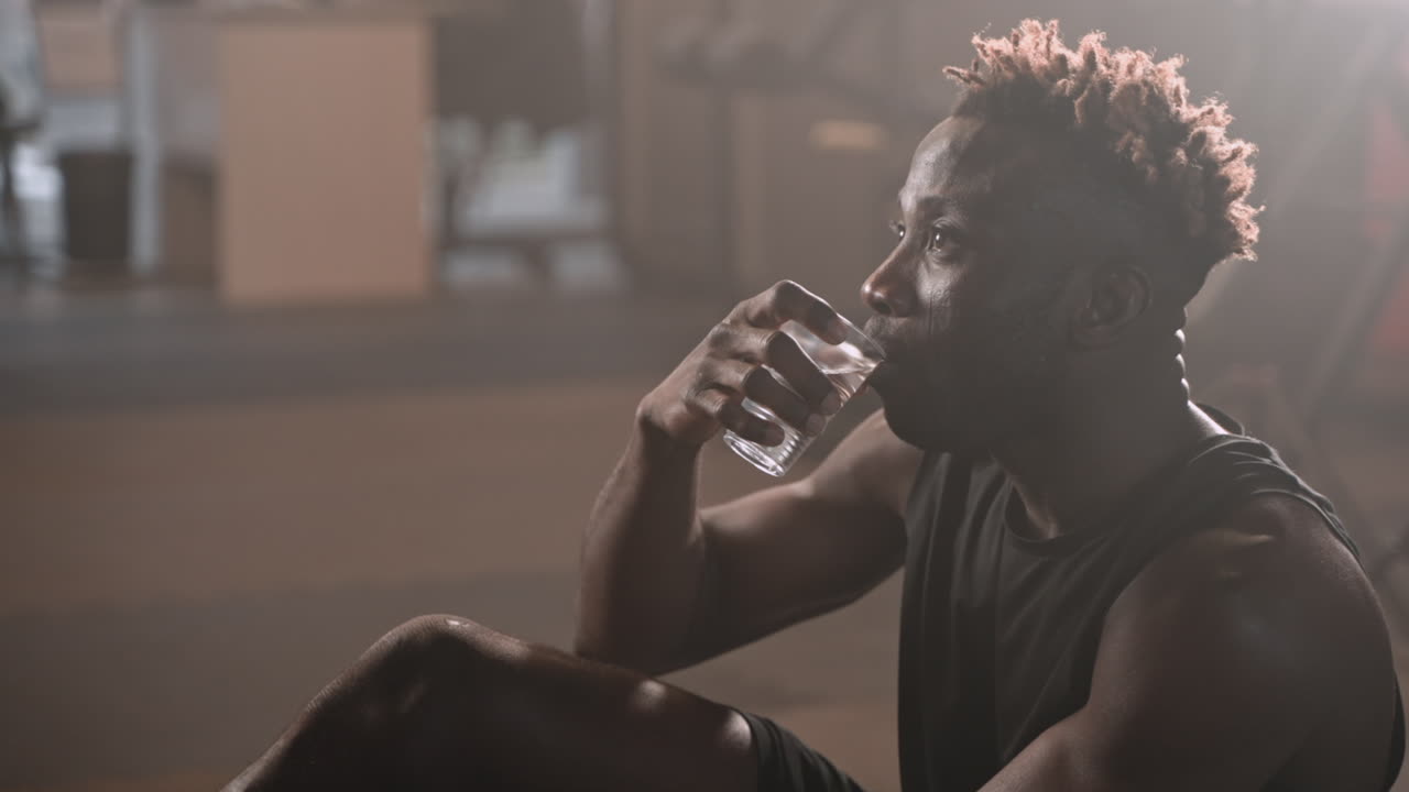 Man Resting and Drinking Water in a Gym