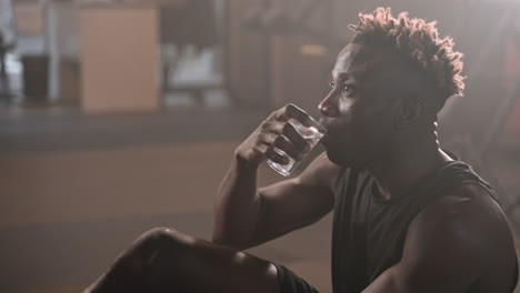 man resting and drinking water in a gym