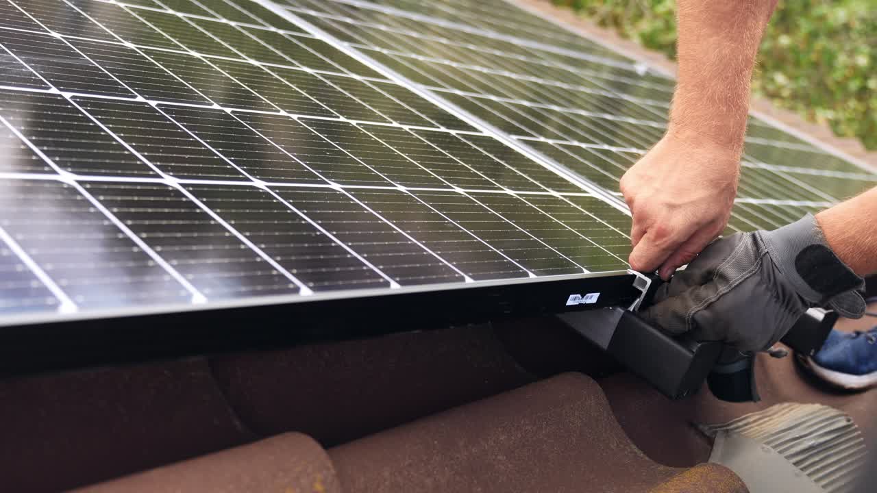 Engineer fixing solar panel cells on rooftop with his hands, close up view