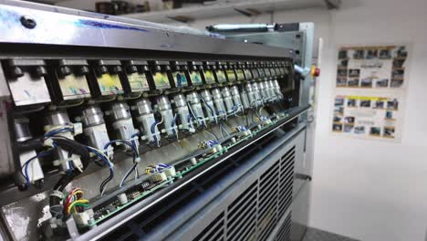 industrial printing machine with a downward tilt, close-up of ink injectors on the panel.