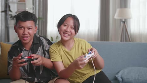 funny asian children with joystick game playing video games on tv at home