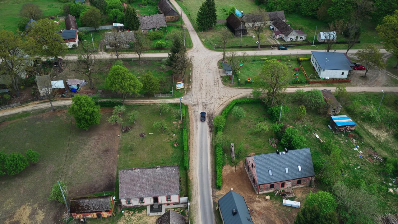 Automobile in transito attraverso un'area residenziale rurale in Polonia - Ripresa con drone