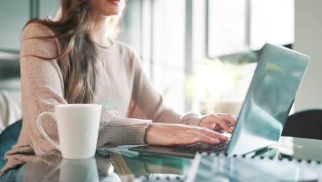 mujer trabajando en una computadora portátil con café