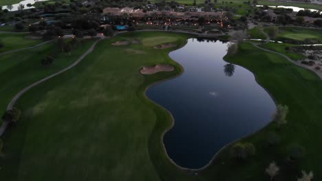 Drone footage from a golf course near a residential neighborhood in Arizona. High aerial shot of the greens, fairway and water hazard