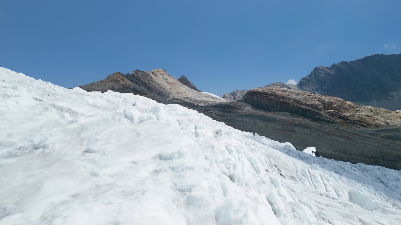 A thrilling, low-altitude aerial drone shot flies closely over the heavily crevassed and textured ice surface of the massive Pastoruri Glacier in the Peruvian Andes