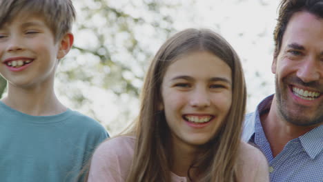 portrait of family on summer walk sitting on wooden fence in countryside