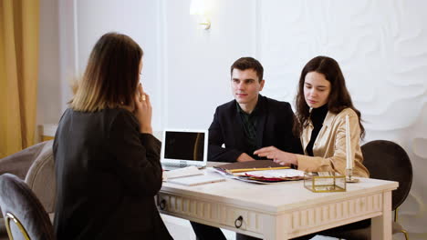 asian woman showing a sample book to a couple