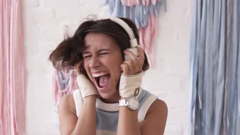 brunette girl going crazy while listening to music in her headphones. shaking her head intensly and shouting out loud. indoors