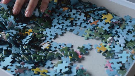 woman hand browsing through colorful jigsaw puzzle game pieces slow motion 50i