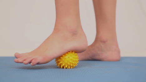 girl using yellow massage ball on her foot