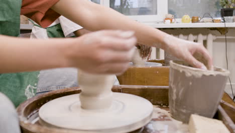 ワーク ショップでろくろで陶器の作品をモデリング緑のエプロンを身に着けている従業員の手 1