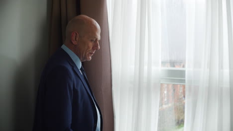 wide shot of a pensive thoughtful mature man looks out of a window