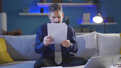 Mature-businessman-looking-carefully-at-work-papers-and-laptop-seriously-and-professionally-receives-bad-news.