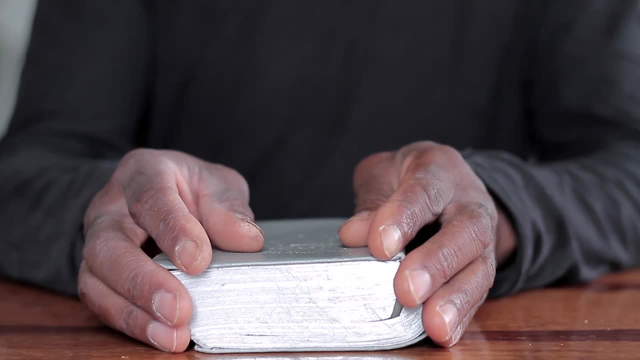 hombre negro orando a dios con la biblia en las manos hombre caribeño orando con el fondo con la gente stock video stock footage