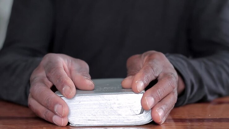 black man praying to god with bible in hands caribbean man praying with background with people stock video stock footage