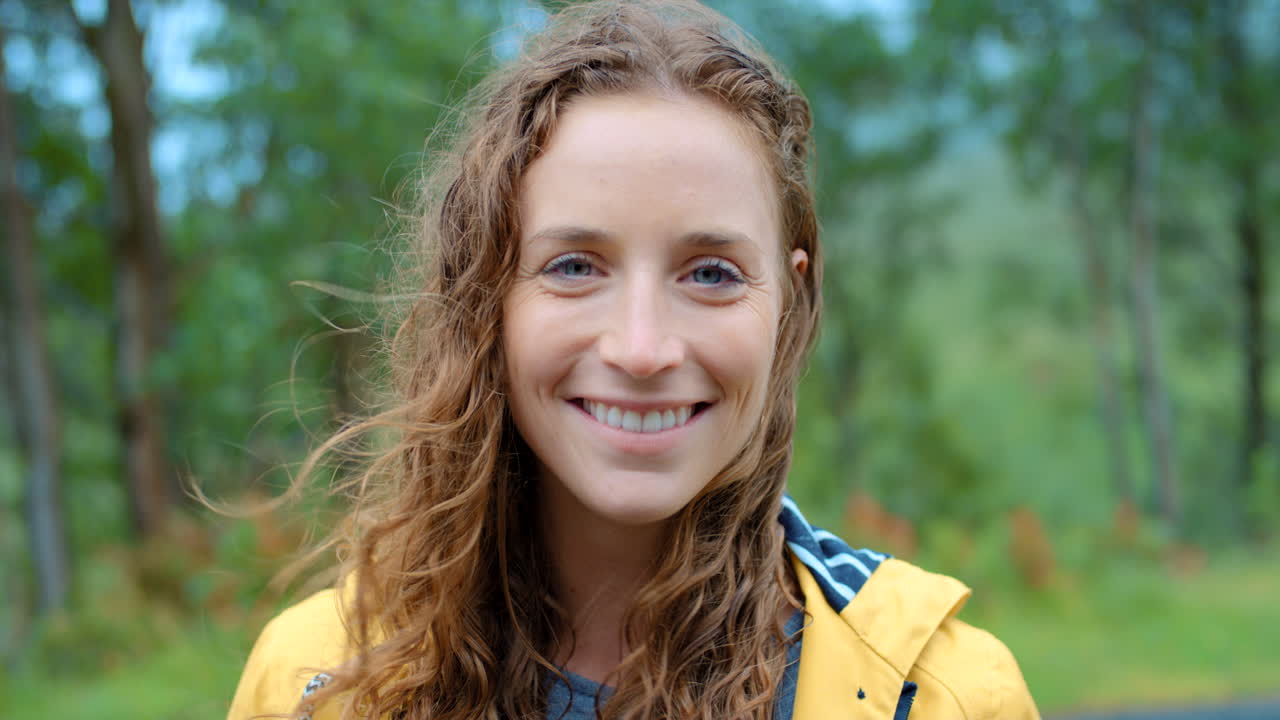 mujer sonriendo en un impermeable amarillo afuera en un día de lluvia