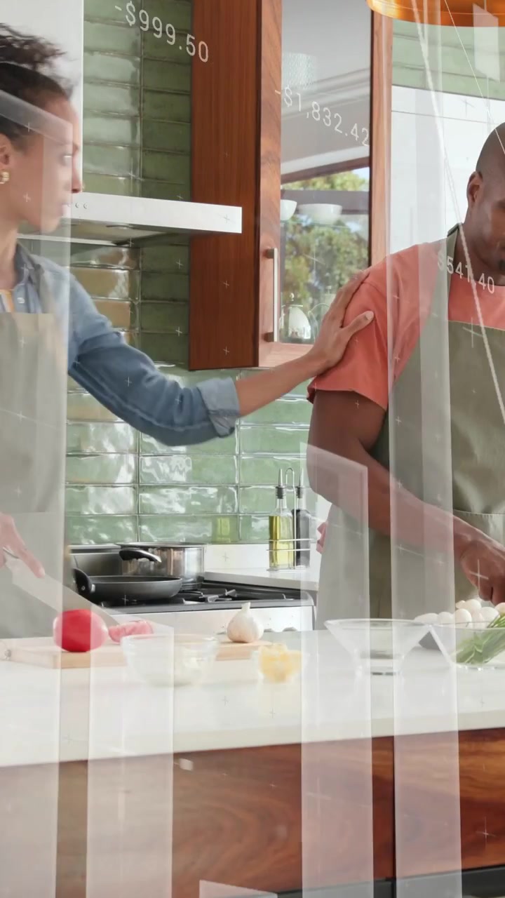Video verticale: Coppia che taglia gli ingredienti iniziando la preparazione del pasto, mentre grafici finanziari si visualizzano sulle mani sopra il bancone.