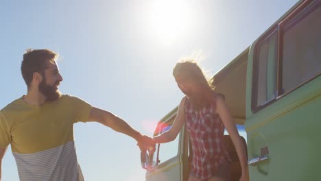 una joven pareja feliz tomándose de las manos y saliendo de la furgoneta 4k