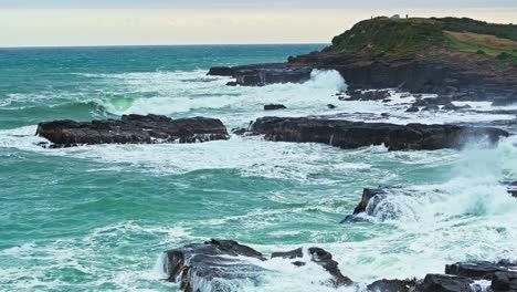 Aerial-pullback-above-powerful-ocean-waves-crashing-against-black-rocks