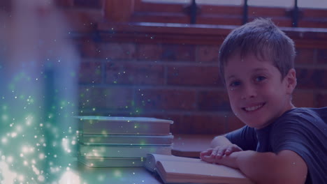 animation of glowing spots over smiling caucasian boy reading book