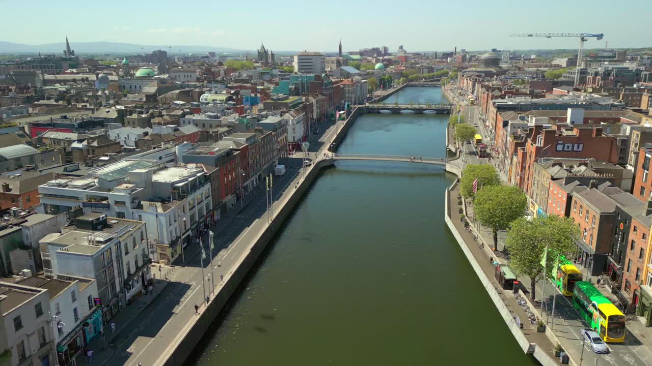 Wide, forward travelling aerial video of the River Liffey, various bridges and Dublin City Centre in Dublin, Ireland on a bright and sunny day. Filmed in 4K, 60FPS and with Rec709 color.
