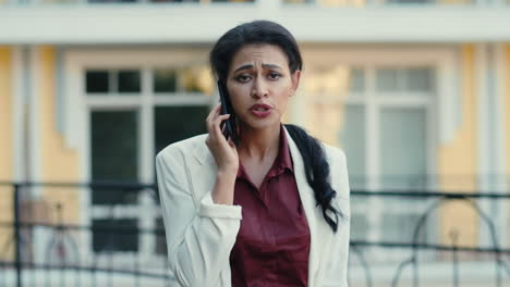 irritated businesswoman talking over cellphone at urban street