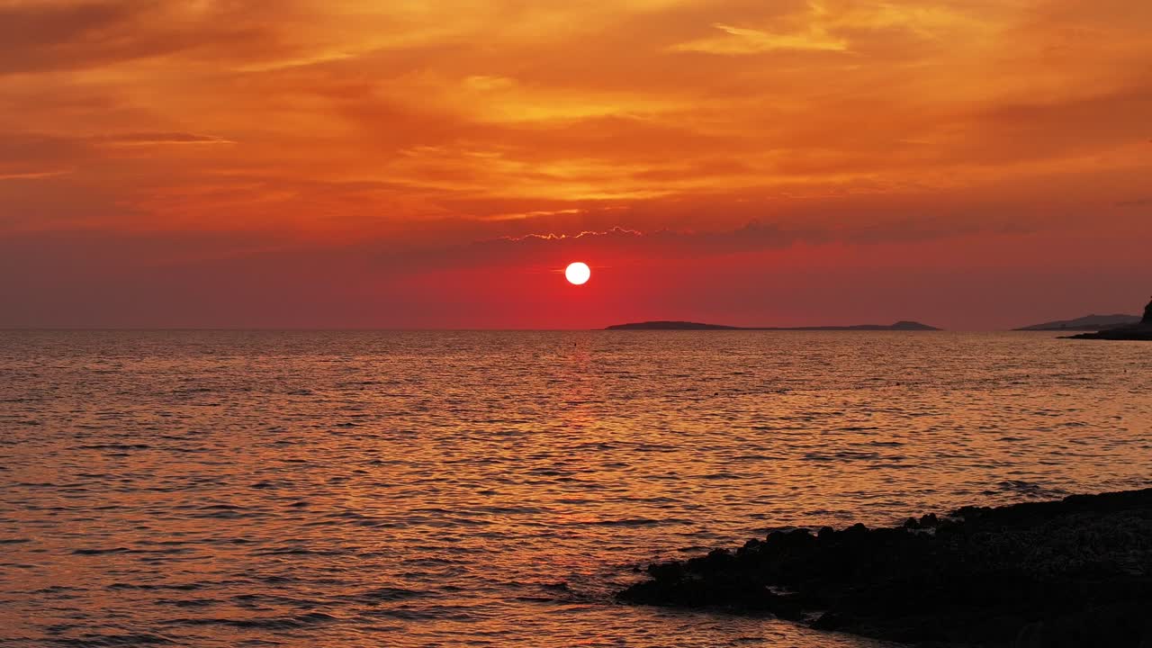 Experience the magic of a coastal sunset from above, with vibrant hues lighting up the sky as waves gently crash against the shore. This drone footage highlights the calm beauty of the evening