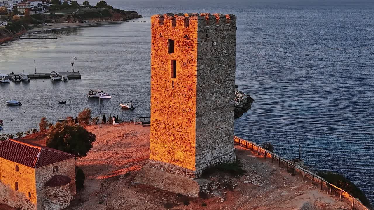 Torre na Grécia perto da água e barcos durante o pôr do sol