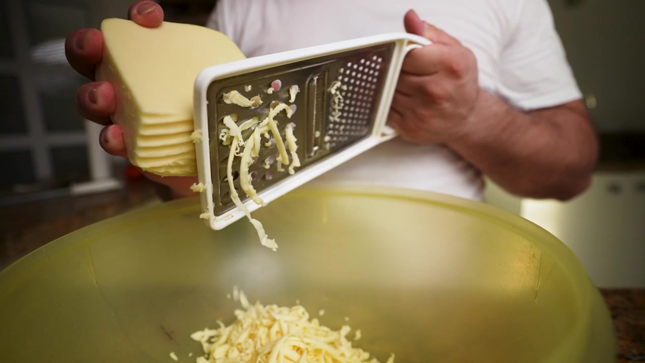 Primo piano di uno chef che usa una grattugia per formaggio per preparare scaglie di formaggio fini per un capolavoro culinario