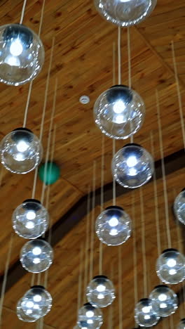 lamps hanging on celling. wood background. warm light. modern design. transparent round glass celling lamps. wooden celling. modern design. video from below. vertical video