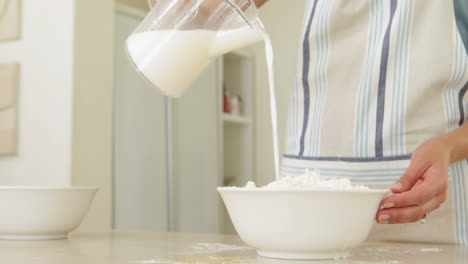 Woman-pouring-milk-into-bowl-of-flour