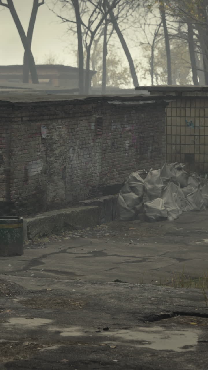 Una vista sombría de un edificio de ladrillo abandonado en un entorno urbano neblinoso