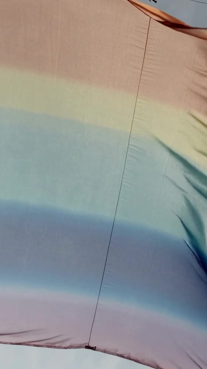 Vídeo vertical: Bandeira listrada pálida esvoaçando, ondulando e alisando com o vento ao ar livre, com costura e prendedor.