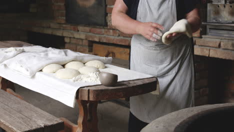 woman baker's hands flatten the dough and sticks it on the hot surface of a round clay oven