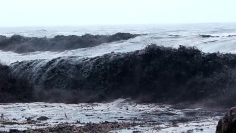 black wave breaking in the ocean with river debris