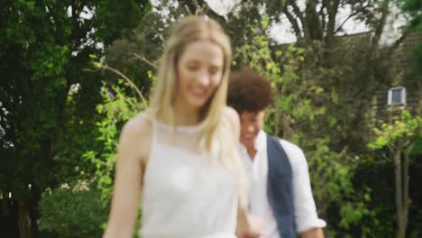 happy diverse couple walking in garden on sunny day at wedding