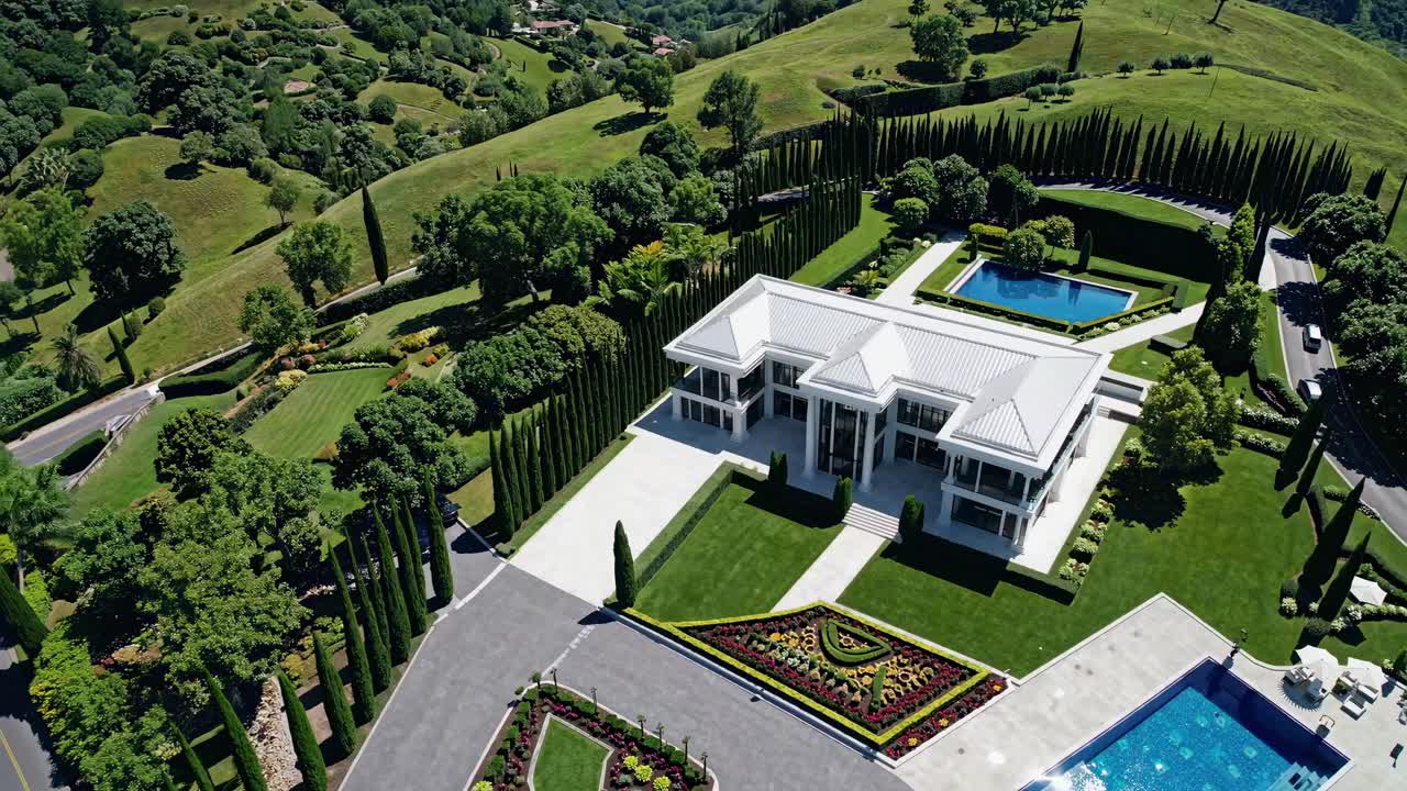 Aerial view of a luxurious modern villa surrounded by lush greenery, manicured gardens, and sparkling pools, showcasing elegant architecture and serene outdoor spaces