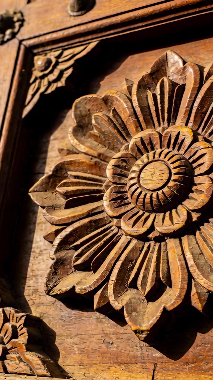 Dikey video: Metal bağlantı elemanlı bir panel üzerindeki oyma çiçek rozetini gösteren, yukarı doğru başlayan kamera eğimi.