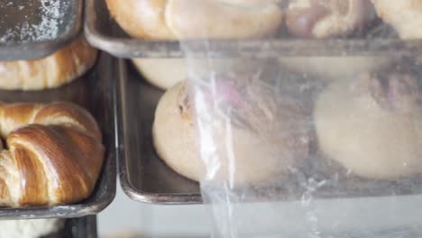 freshly baked croissants and bread cooling on metal baking trays in a bakery