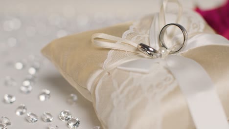 close up of wedding rings for bride and groom on small decorated cushion 1