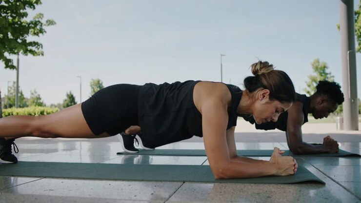 Starting frame, woman and man holding forearm plank on mats at shelter training in sportswear